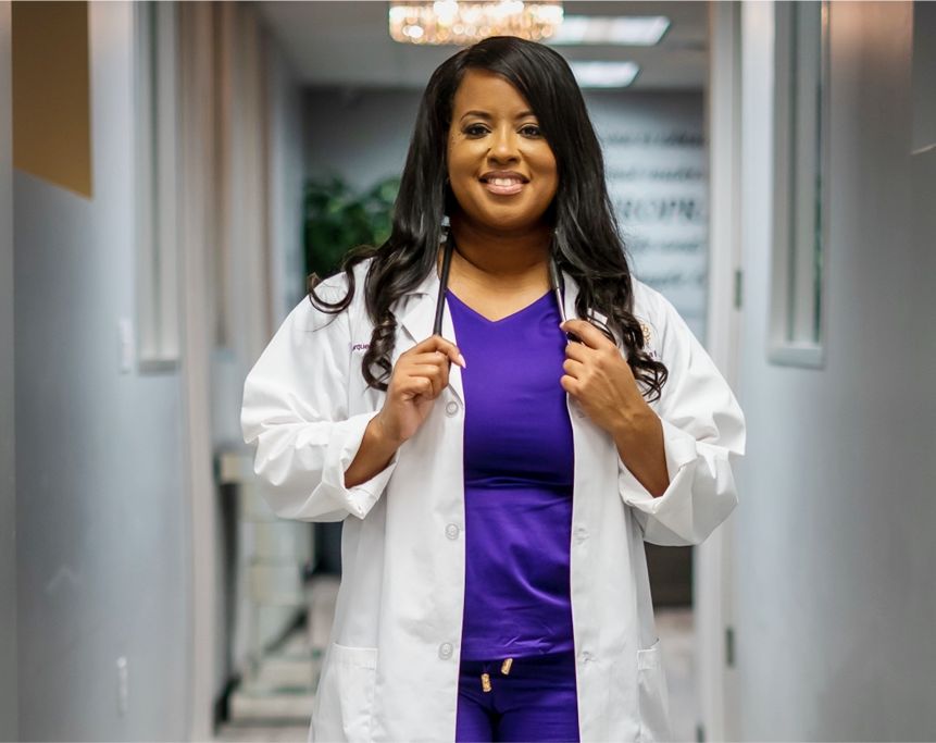 A woman in purple scrubs and white lab coat.