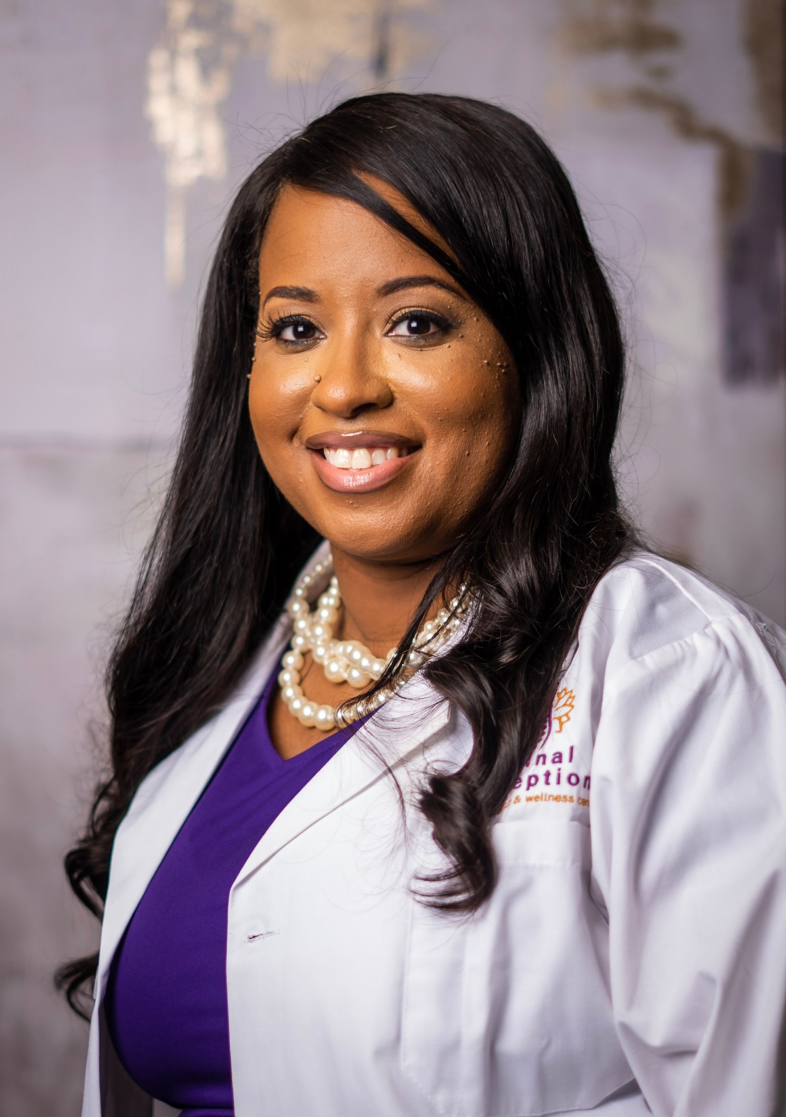 A woman in white lab coat and purple shirt.