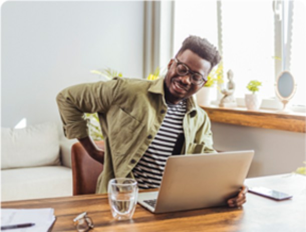 A man sitting at a table with his back turned looking at the laptop.